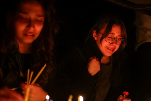 Girls cry as they light candles in the town of Kocani, North Macedonia, Sunday, March 16, 2025, following a massive fire in the nightclub early Sunday. (AP Photo/Armin Durgut)