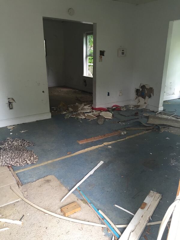 The front door of the house owned by Ilimite, LLC has been left open, revealing holes in the wall and discarded liquor bottles.