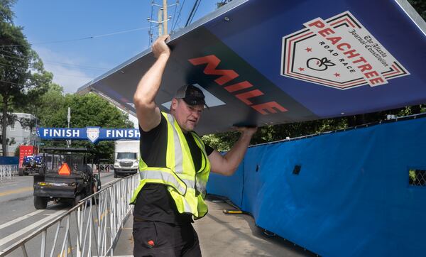 John DeLay prepares AJC Peachtree Road Race signage on Tuesday morning.