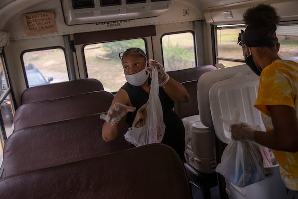 Sparta City Councilwoman Sandra Sherrod (left) is tossed by the rumbling of the school bus as she works with T'Anna Harris, a paraprofessional at Hancock Central Middle School, to sort and prepare bagged lunches to be delivered to Hancock County Schools District students in Sparta. She has recovered from COVID-19. (ALYSSA POINTER / ALYSSA.POINTER@AJC.COM)