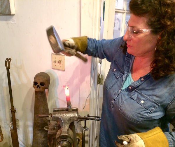 Artist Corrina Sephora pounds out the heated metal of an AR-15 barrel to create flower buds. Photo by Bill Torpy