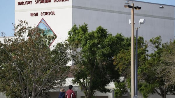 Charles Lambeth, left,and Joey Wong, alumni of Marjory Stoneman Douglas High School, gaze at the school Sunday in Parkland, Florida.