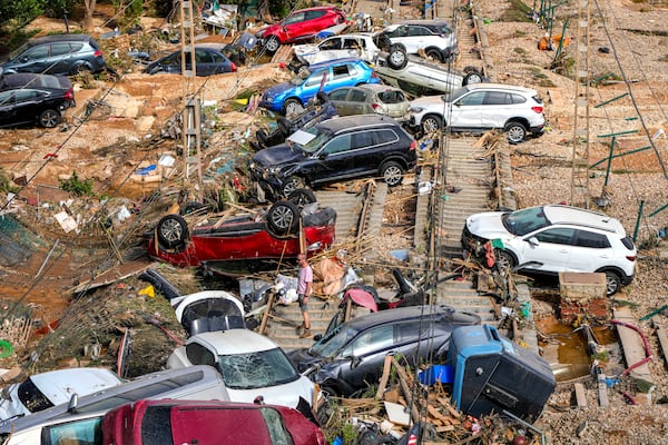 A man stands among flooded cars piled up in Valencia, Spain, Thursday, Oct. 31, 2024. (AP Photo/Manu Fernandez)