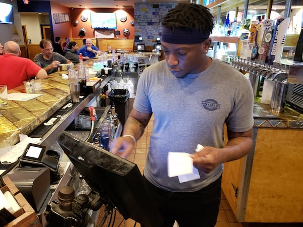 The coronavirus outbreak has cut into consumers’ willingness to venture out to restaurants and bars. That’s cutting into the work available for people like bartender Quan Smith, a Lawrenceville resident who attends Georgia Gwinnett College and works near Duluth. MATT KEMPNER / AJC