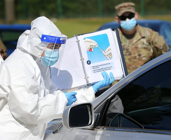 Walmart pharmacist Shama Sarangi instructs a motorist how to do a self swab with Georgia Army National Guard Pfc. Joshua Tucker looking on at a new mobile COVID-19 drive-through testing site to serve rural stretches of Georgia in communites without access to testing at Diamond Lakes Regional Park on Monday, April 27, 2020, in Hephzibah near Augusta. CURTIS COMPTON / CCOMPTON@AJC.COM