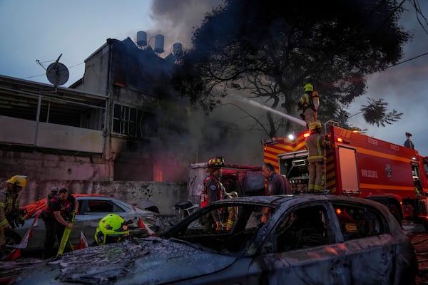 Firefighters work to extinguish a fire after a rocket fired from Lebanon hit Kiryat Ata, northern Israel, on Monday, Nov. 11, 2024. (AP Photo/Francisco Seco)