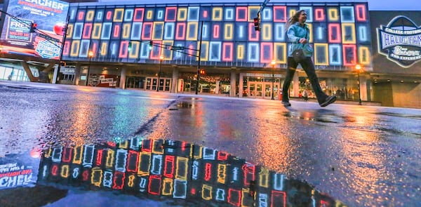 File photo: Jennifer Toland from Boise, Idaho crosses Marietta Street in front of the colorful facade of the College Football Hall of Fame in downtown Atlanta earlier this year. JOHN SPINK/JSPINK@AJC.COM