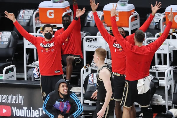 Injured Hawks guard Trae Young (bottom, left) and the bench react as Kevin Huerter hits a three to extend Atlanta's lead over the Milwaukee Bucks during the fourth quarter of Game 4 of the Eastern Conference finals Tuesday, June 29, 2021, in Atlanta. The Hawks evened the series 2-2 with a 110-88 victory. (Curtis Compton / Curtis.Compton@ajc.com)