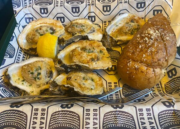 The charbroiled oysters at Breaker Breaker are drenched in garlic butter and melted Parmesan. Ligaya Figueras/ligaya.figueras@ajc.com