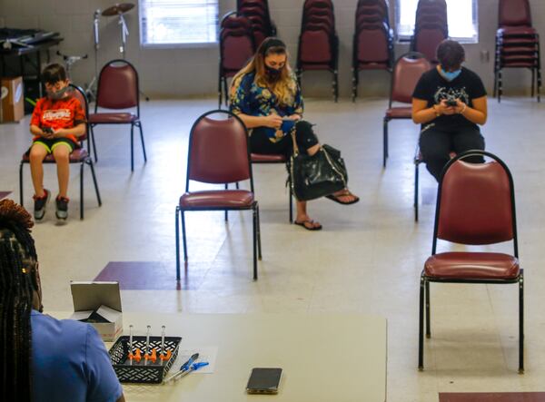 In this file photo, London Blum, 12, seated right, waits with her family for the CORE nurse to dilute and divide the vaccine before London receives her first Pfizer vaccination at The Nett Church in Lilburn. (Jenni Girtman for The Atlanta Journal-Constitution