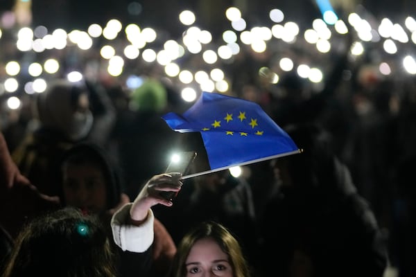 A demonstrator holds the EU flag during a rally outside the parliament's building to protests against the government's decision to suspend negotiations on joining the European Union, in Tbilisi, Georgia, Wednesday, Dec. 4, 2024. (AP Photo/Pavel Bednyakov)