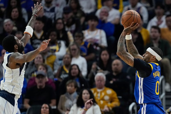 Golden State Warriors guard Gary Payton II, right, shoots a 3-point basket over Dallas Mavericks guard Kyrie Irving during the first half of an NBA basketball game Sunday, Feb. 23, 2025, in San Francisco. (AP Photo/Godofredo A. Vásquez)