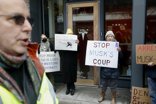 FILE - People protesting Elon Musk's actions in the Trump administration hold signs outside a Tesla showroom in Seattle on Thursday, Feb. 13, 2025. (AP Photo/Manuel Valdes, File)