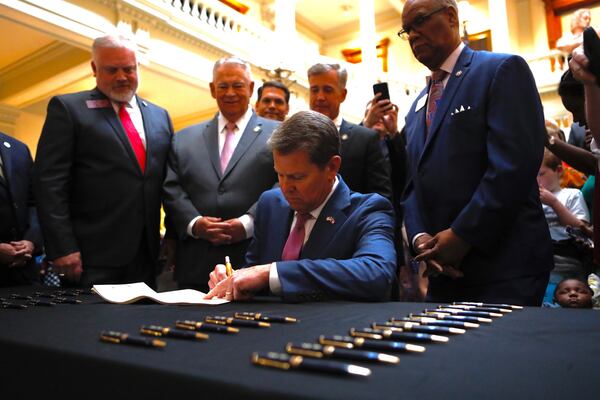 Georgia Gov. Brian Kemp signed a bill legalizing cultivation and sales of medical marijuana oil. Kemp was surrounded by several state legislators as he signed House Bill 324 at the state Capitol on Wednesday, April 17. From left: State Reps. Micah Gravley, David Ralston, Mark Newton and Calvin Smyre. BOB ANDRES / BANDRES@AJC.COM