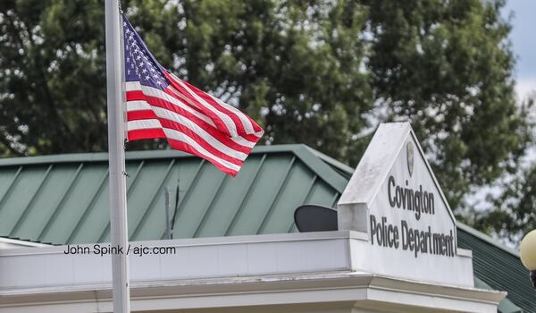 The American flag is flown at half-staff Monday at the Covington Police Department as Officer Matt Cooper is moved to Grady Memorial Hospital. JOHN SPINK / JSPINK@AJC.COM