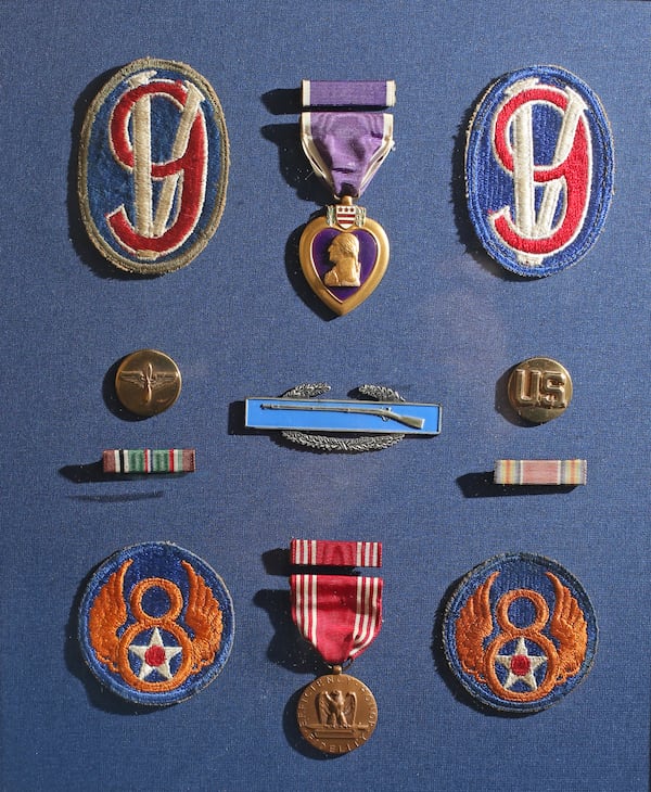 Some of Eddie Sessions' medals and badges, including the Purple Heart (top row center) and the emblem of the 95th Infantry Division (top row right and left).