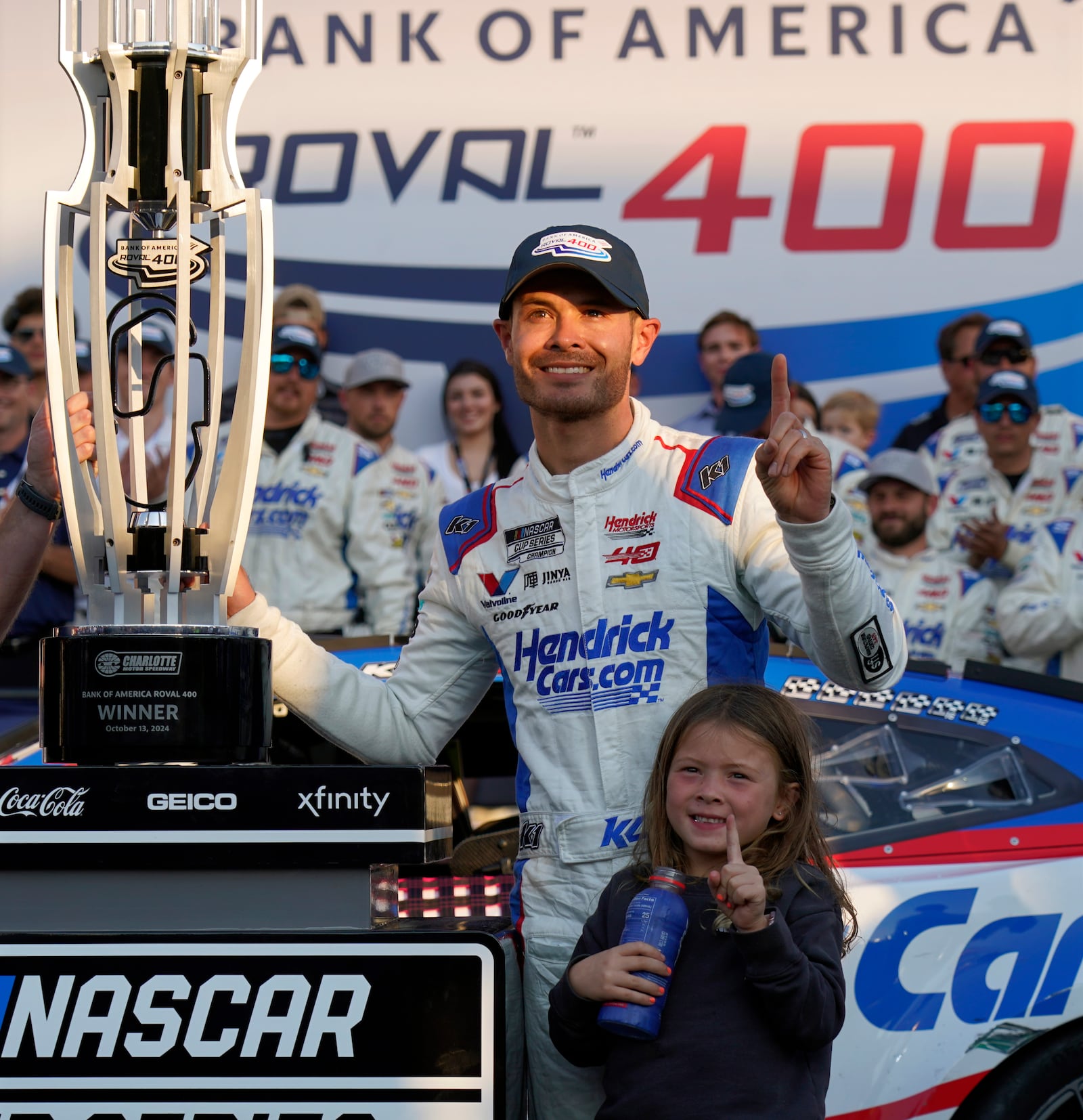 Kyle Larson poses with the trophy with his daughter Audrey, 6, after winning a NASCAR Cup Series auto race at Charlotte Motor Speedway in Concord, N.C., Sunday, Oct. 13, 2024. (AP Photo/Chuck Burton)