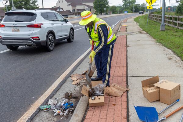 Anthony "Spark Plug" Thomas cleans up litter and debris at the Highway 92 traffic circle at Antioch and Lockwood roads in Fayetteville. (Phil Skinner for the AJC) 