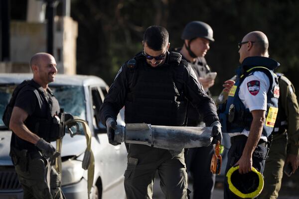 A member of the Israeli security forces carries a piece of a projectile extracted from the site where a rocket, fired from Lebanon, hit an area in the town of Nahariya, northern Israel, Thursday, Nov. 21, 2024. (AP Photo/Leo Correa)