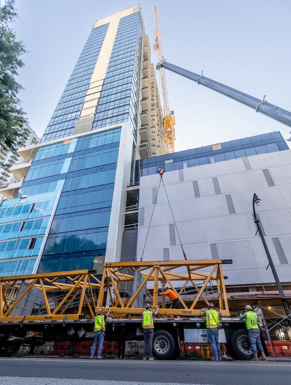 Juneau workers begin disassembling a crane used to construct the Society Atlanta Building at 811 Peachtree Street. A construction project that got underway on Wednesday, May 29, 2024 in Midtown Atlanta will close a portion of Peachtree Street for several days, officials said. The closure, which began at 9 a.m. Wednesday on Peachtree Street from 5th Street to 6th Street, Officials said Peachtree Street would reopen by 4 p.m. Saturday. Police officers will be at the scene to help with traffic, officials said. (John Spink/AJC)