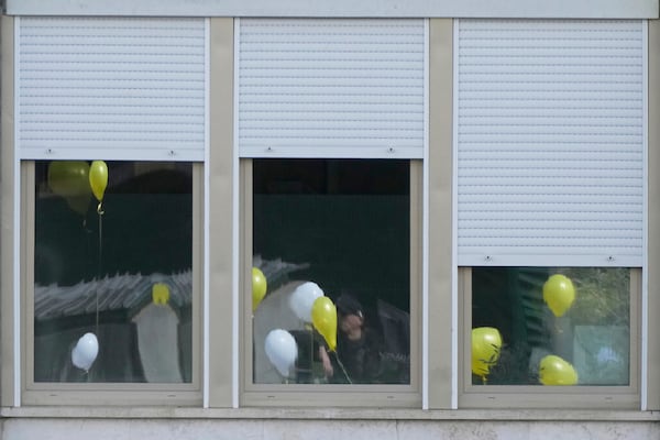 Balloons with the colours of the Vatican flag are reflected on the windows of the Agostino Gemelli polyclinic as faithful pray for Pope Francis in Rome, Sunday, March 16, 2025. (AP Photo/Gregorio Borgia)