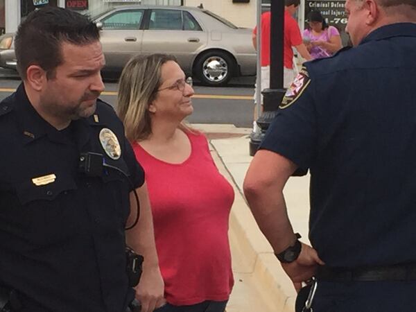 Hapeville City Councilwoman Ruth Barr talks with officers on Aug. 4, 2016, outside City Hall at the city s night out on crime event. Detective Justin McGinnis, left, investigated a bad check case involving Barr and his signature is on a July 6 arrest warrant for Barr that officers later failed to execute. The department's handling of the warrant is under review. Brad Schrade/AJC