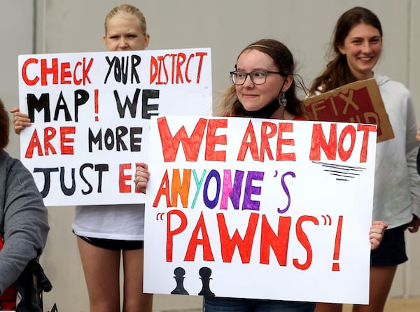 Jordan Ricks, a Druid Hills High School ninth grader, top left, and junior Shannon Gomez, center, hold up signs in support of calls for renovations of their aging school building. The protest was outside of a DeKalb County Board of Education meeting at the district's headquarters in Stone Mountain, Georgia, on April 18, 2022. (Jason Getz / Jason.Getz@ajc.com)