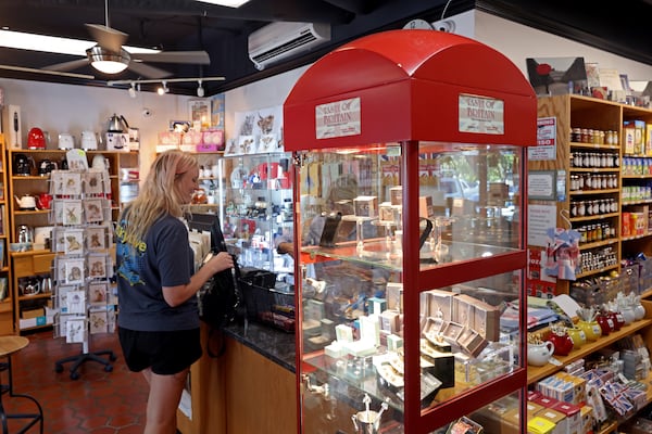 Wendy Tribble, of Suwanee, buys British-themed items for her father at the Taste of Britain shop in Norcross. Rukhsana Aguilar, the shop's owner, says that the queen's death has prompted a flurry of sales on goods featuring her likeness, with items commemorating the Platinum Jubilee especially popular.  (Jason Getz / Jason.Getz@ajc.com)