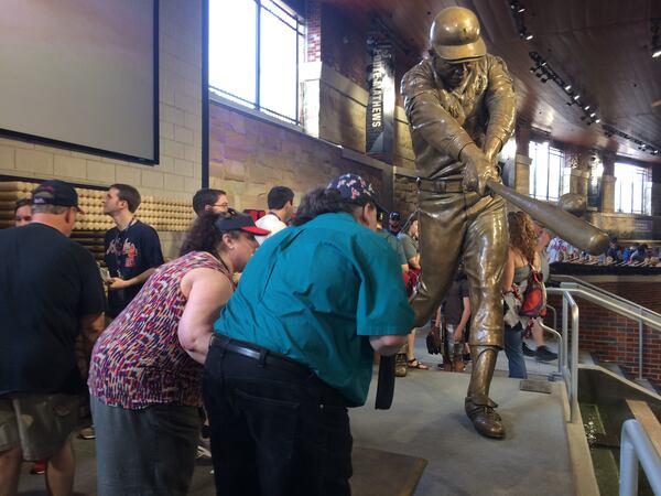 Jennifer Stuckey gives her husband the lowdown on the new Hank Aaron statue located in Monument Garden inside SunTrust Park. Joey Stuckey, who is blind, would check out the bronze statue in great detail, right down to feeling the bat and noting the stitches on the baseball. Photo by Jill Vejnoska/jvejnoska@ajc.com