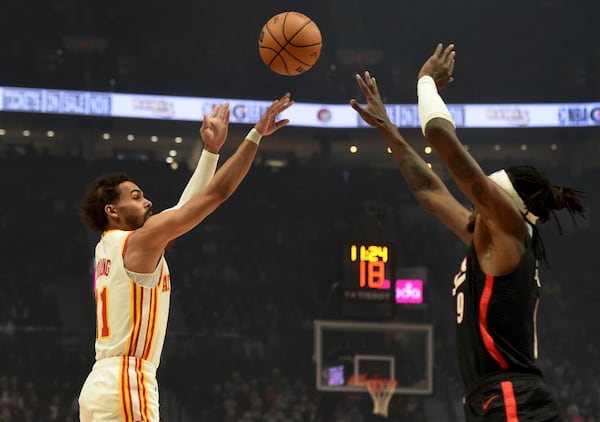 Atlanta Hawks guard Trae Young, left, shoots the ball over Portland Trail Blazers forward Jerami Grant, right, during the first half of an NBA basketball game in Portland, Ore., Sunday, Nov. 17, 2024. (AP Photo/Steve Dykes)