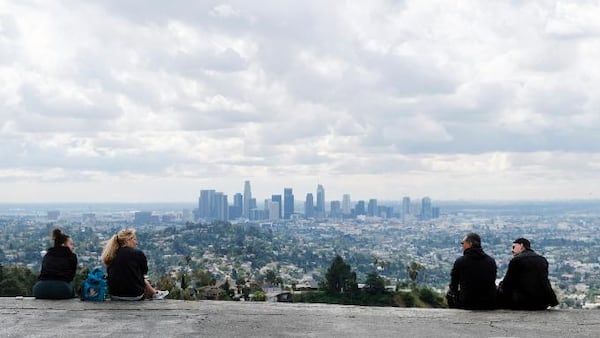 Two pairs of hikers maintain distance as they mingle at Vista View Point in Griffith Park, Friday, March 20, 2020, in Los Angeles. California Gov. Gavin Newsom issued a statewide stay-at-home order Thursday for residents to venture outside only for essential jobs, errands and some exercise, due to coronavirus concerns. (AP Photo/Chris Pizzello)