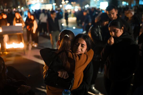 People hug as they wait in lines to light candles in the town of Kocani, North Macedonia, Sunday, March 16, 2025, following a massive fire in the nightclub early Sunday. (AP Photo/Armin Durgut)