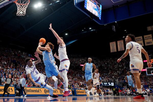 North Carolina guard Seth Trimble (7) shoots under pressure from Kansas center Hunter Dickinson, right, and guard Rylan Griffen (6) during the second half of an NCAA college basketball game Friday, Nov. 8, 2024, in Lawrence, Kan. Kansas won 92-89. (AP Photo/Charlie Riedel)