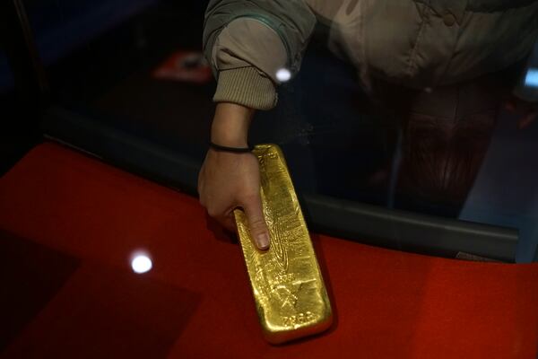 A visitor tries to pick up a gold bar at Sado Kinzan Gold Mine historic site in Sado, Niigata prefecture, Japan, Saturday, Nov. 23, 2024. (AP Photo/Eugene Hoshiko)