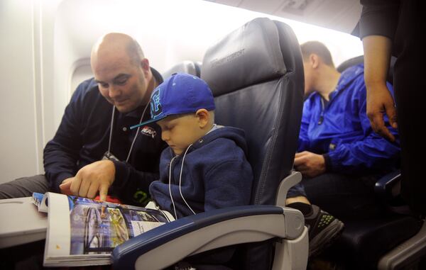 Dec. 6, 2014, Atlanta: Richmond Davis and his son Jake, 7, read a magazine together as they wait for flight 9707 to take off at Hartsfield-Jackson Atlanta International Airport's Maynard H. Jackson International Terminal Saturday, Dec. 6, 2014. Delta and Children's Healthcare of Atlanta "flew" about 40 children from the Atlanta area to the "North Pole" to visit Santa's village Saturday. BITA HONARVAR / BHONARVAR@AJC.COM