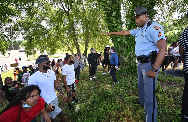 A Georgia State Patrol officer tries to stop a group of protesters on Saturday, June 13, as they climb up to Interstate 85 near the Wendy's where Rayshard Brooks was shot and killed by Atlanta police. (Hyosub Shin / Hyosub.Shin@ajc.com)