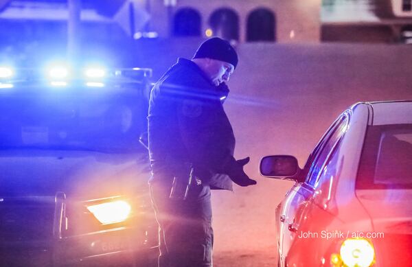 Officers are stopping vehicles coming out of an area subdivision to make sure  two men are not hiding inside them. JOHN SPINK / JSPINK@AJC.COM