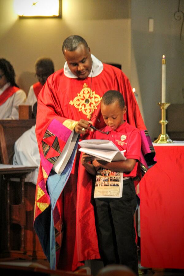 The Rev. Charles L. Fischer III looks on as his son Charles IV reads a litany of prayer during services at St. Paul’s Episcopal Church, where Fischer is pastor. CONTRIBUTED