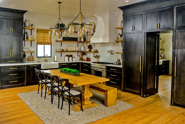 The sprawling kitchen doubles as a breakfast nook with a wooden table, chairs and bench. Black cabinets line the wall and the doorway to the butler's pantry, and a dramatic white hood hangs over a Thermador range. Text by Marena Galluccio/Fast Copy News Service.(Christopher Oquendo/www.ophotography.com)