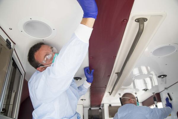 David Beranek (left), operation field supervisor at Metro Atlanta Ambulance Services, uses a germicidal disposable wipe to clean the inside of an ambulance while demonstrating how paramedics will disinfect their vehicles following a transport of a patient with coronavirus. (ALYSSA POINTER/ALYSSA.POINTER@AJC.COM)