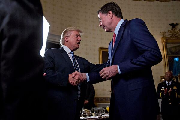 President Donald Trump shakes hands with then-FBI director James Comey during an Inaugural Law Enforcement Officers and First Responders Reception in the Blue Room of the White House on January 22, 2017 in Washington, DC. 