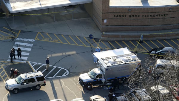 In this Dec. 14, 2012, file photo, officials stand outside of Sandy Hook Elementary School in Newtown, Connecticut, where Adam Lanza, 20, gunned down 20 children and six educators before killing himself. Documents from the investigation into the Sandy Hook shooting are shedding light on Lanza’s anger, scorn for other people and deep social isolation in the years leading up to the shooting. He fatally shot his mother, Nancy Lanza, at their home before driving to the school.