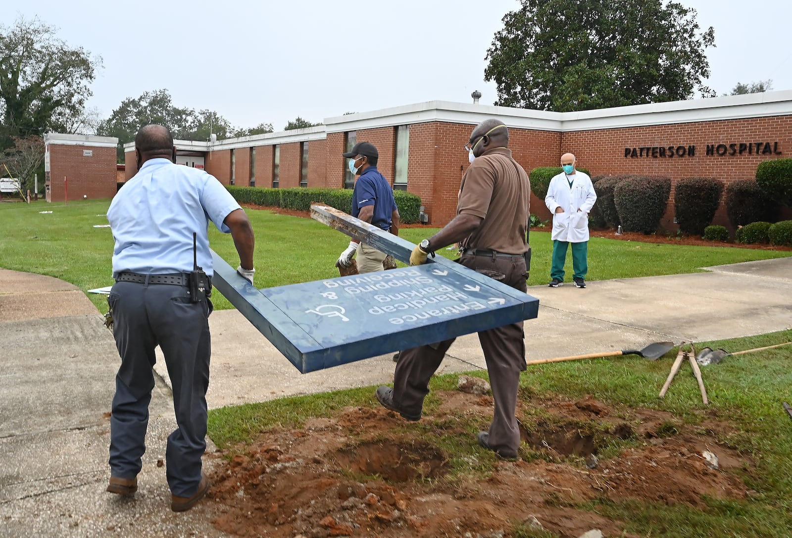 Dr. Abdollatif Saleh Ghiathi, right, watches as hospital maintenance staff, from left, Bruce Green, Jimmie Fair Sr. and Jerry Daniels remove a sign outside the Southwest Georgia Regional Medical Center on Thursday, the day the hospital officially closed. (Hyosub Shin / Hyosub.Shin@ajc.com)