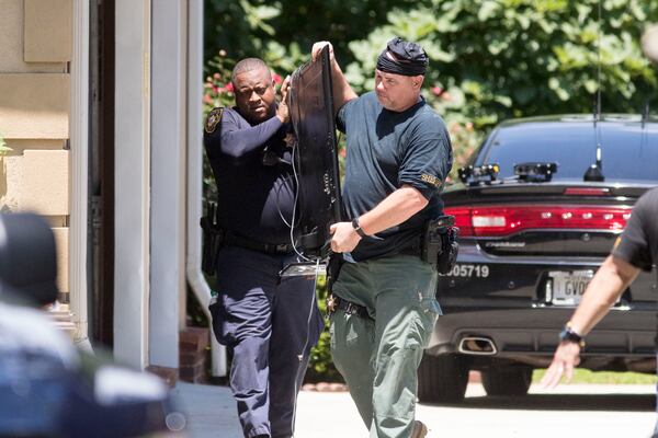 Police officers remove items from a house at 1711 Five Forks Trickum Road that is involved in a multi-residential Gwinnett Metro Task Force raid. ALYSSA POINTER / ALYSSA.POINTER@AJC.COM