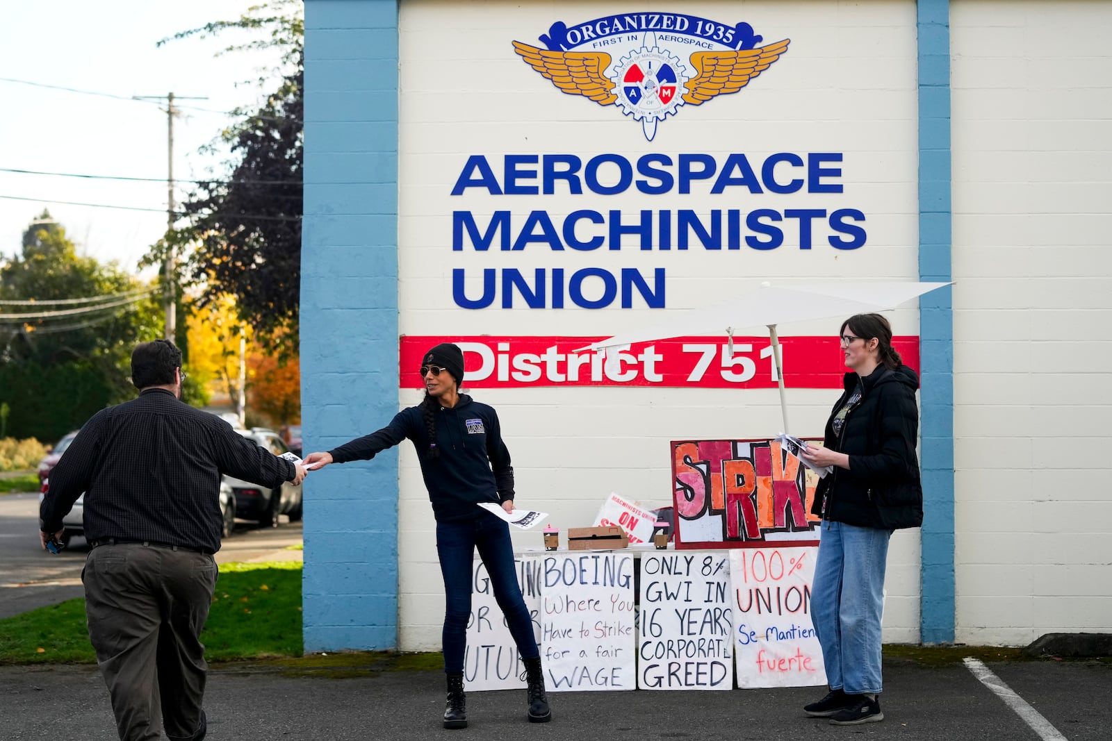 Boeing calibration specialist Eep Bolaño, second from left, and machinist Ky Carlson, right, hand out flyers to other employees arriving to vote on a new contract offer from the company, Wednesday, Oct. 23, 2024, at the Aerospace Machinists Union hall in Renton, Wash. (AP Photo/Lindsey Wasson)