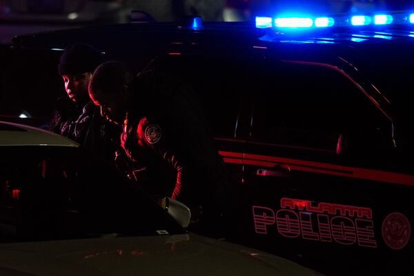 Atlanta officers look inside the victim's vehicle for evidence.