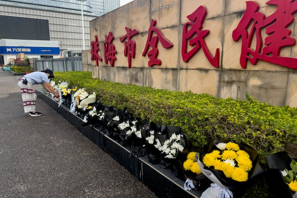 A woman offers flowers outside the "Zhuhai People's Fitness Plaza" where a man rammed his car into people exercising at the sports center, in Zhuhai in southern China's Guangdong province on Wednesday, Nov. 13, 2024. (AP Photo/Ng Han Guan)