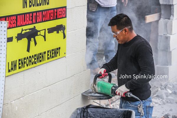 Abimel Lopez with NB Masonry works to repair a massive hole in the side of Gable Sporting Goods in Douglasville after a U-Haul was used as a battering ram in an early Thursday morning burglary.