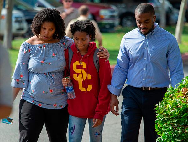 Parents walk with one of the students evacuated from Saugus High School after the shooting.