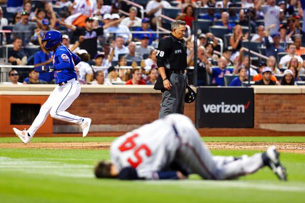 New York Mets' Francisco Lindor scores on a throwing error by Atlanta Braves shortstop Dansby Swanson as Braves starting pitcher Max Fried (54) lies on the ground during the third inning of the second game of a baseball doubleheader Saturday, Aug. 6, 2022, in New York. (AP Photo/Jessie Alcheh)